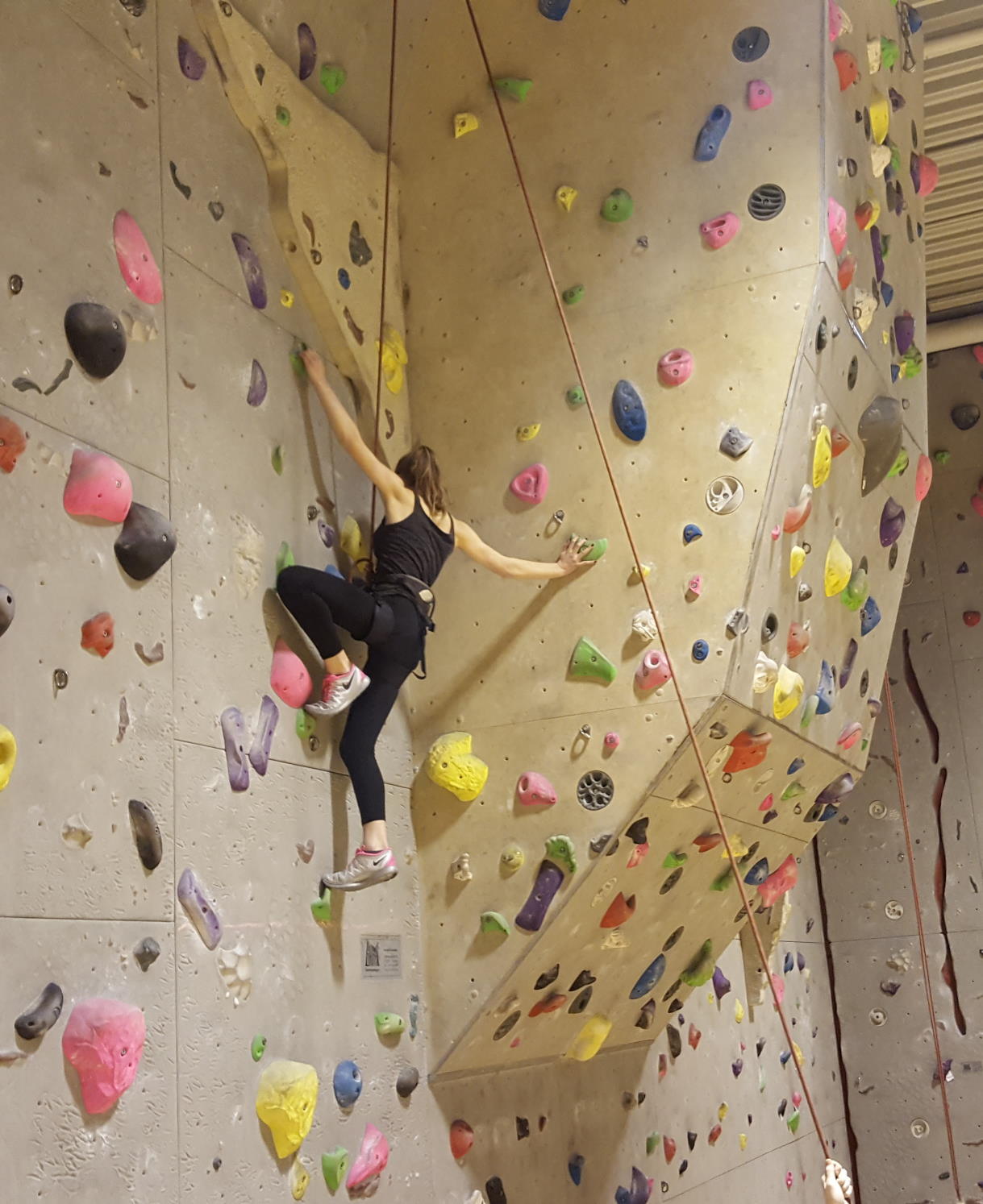 eine Schülering kletter an einer indoor kletterwand