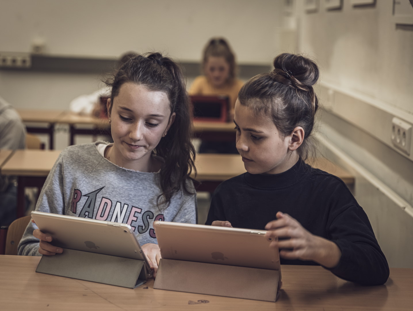 Zwei Schüler tauschen sich über ihre Arbeit an iPads aus